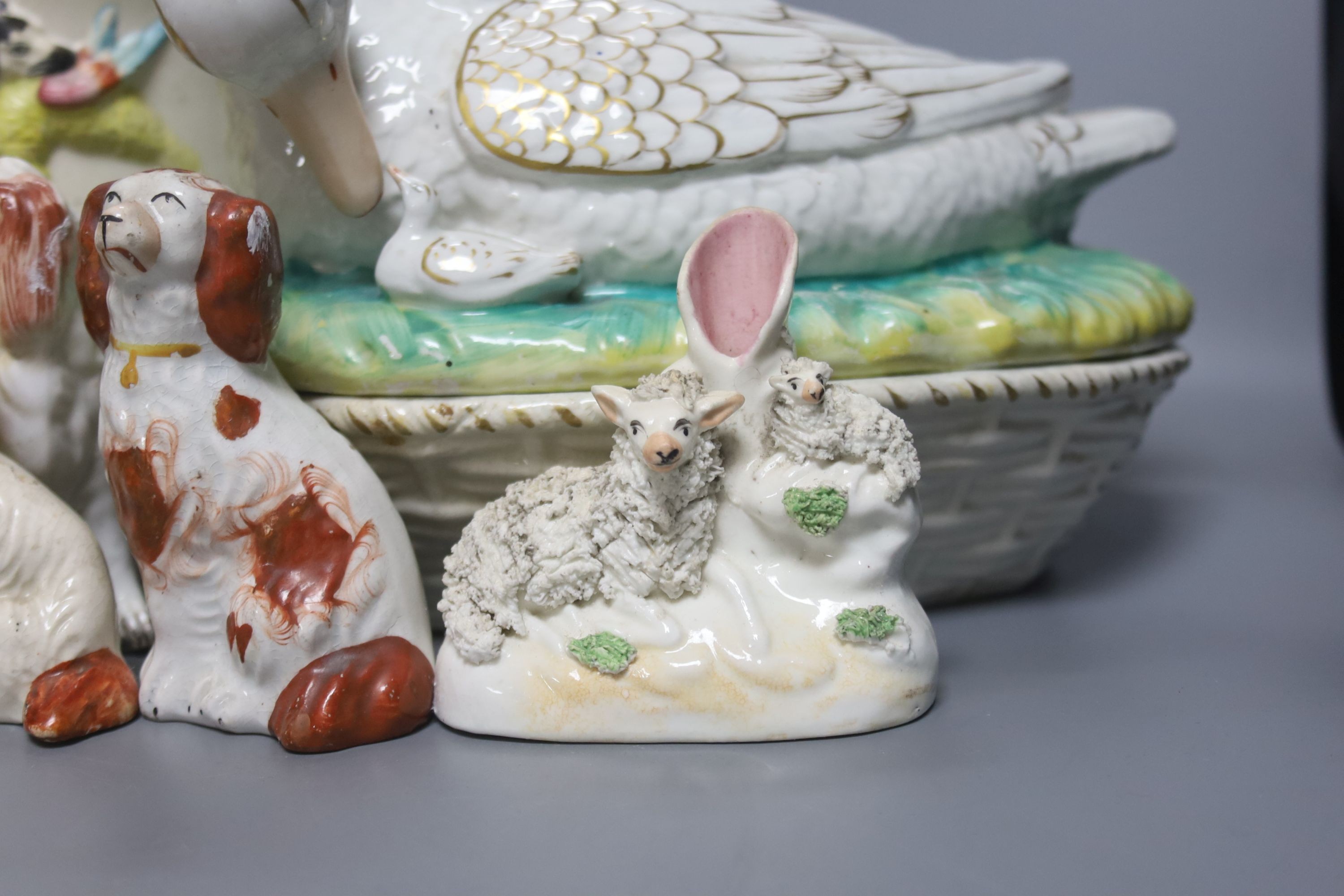 A Staffordshire pottery ‘duck’ tureen and cover, 23cm, a pair of faience candlesticks, Staffordshire figures of dogs, sheep and a zebra and a two handled loving mug